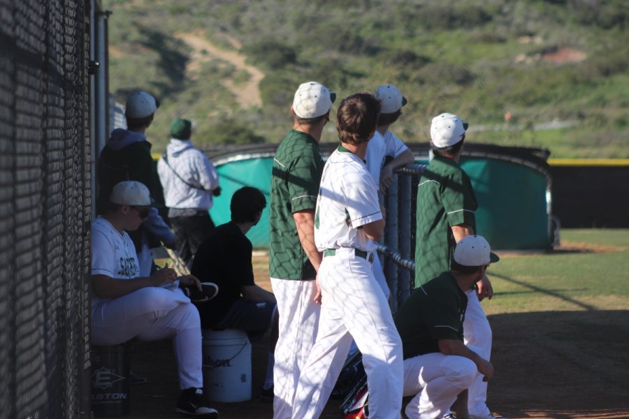 Sage Creek's dugout looks off into the distance as the ball flies and the runs score.