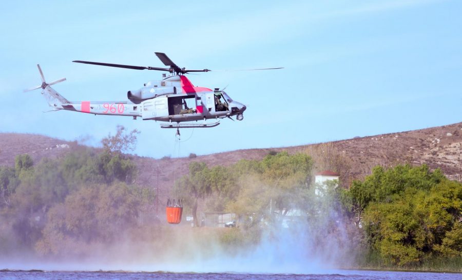 A United States helicopter refills a water bucket for aerial fire fighting efforts. In the midst of the northern San Diego wildfires, United States Marines aided in containment. 