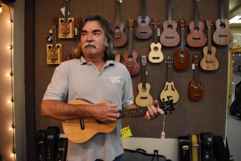 Roy Good plays ukulele inside the shop he has been working at for over three decades.