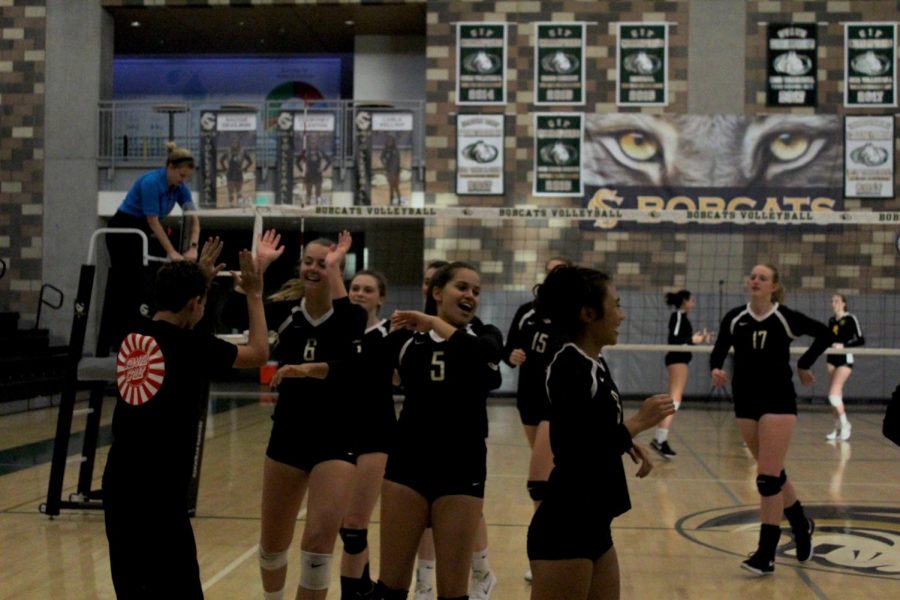 The volleyball team high-fiving one of their fans before the game started. They were gearing up for a tough competition in Patrick Henry.