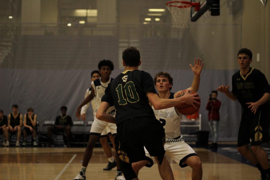 Sage Creek varsity basketball team takes the offense against the Knights with Brady Canfield leading the charge. Even though San Marcos set up a defender, Canfield pressured through to open themselves up for the basket. 