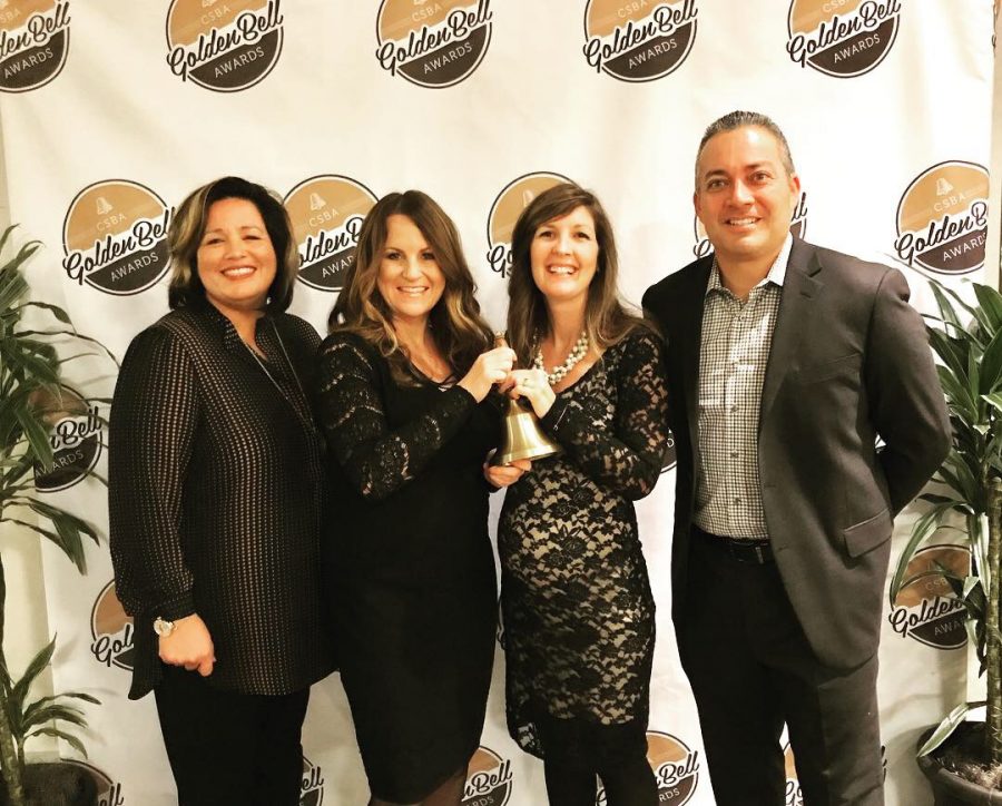 Standing left to right is Claudine Jones, from CUSD Board of Trustees; Shannon Alberts, Sage Creek English teacher; Corrie Myers, Sage Creek English Teacher; and César Morales, Sage Creek Principal. They are holding the Golden Bell Award which the Genius Project was recognized for through the CSBA.