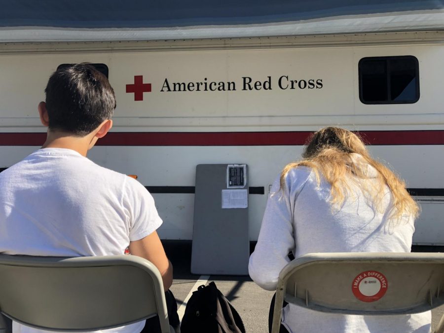 Students fill out forms and wait in front of the American Red Cross blood drive bus for their turn to give blood. On Wednesday, Dec. 19, students left classes throughout the day to donate their blood to the cause.