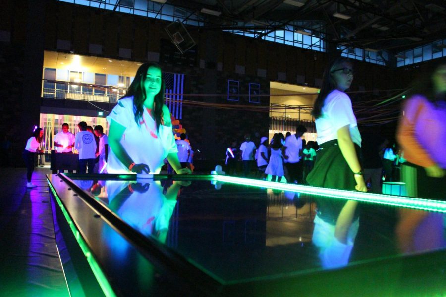 Students take a break from dancing and play light up neon air hockey during MORP. The dance also included activities such as foosball and a photobooth for students to participate in.