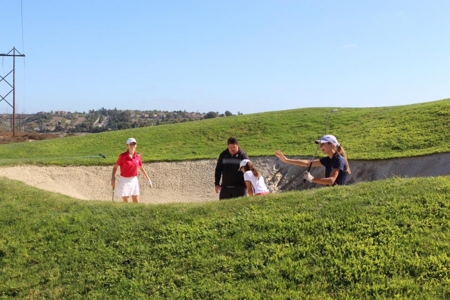 Varsity Girl’s Golf Coach David Walther instructs three of his athletes how to get out of a bunker. These golfers started off at the sand trap to begin their Wednesday afternoon practice at The Crossings. 
