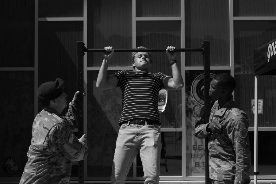 Senior Jonah Shoemaker tests his strength in front of two Army soldiers on the pull-up bars. Army recruiters visited during lunch on Wednesday, Sept. 18.