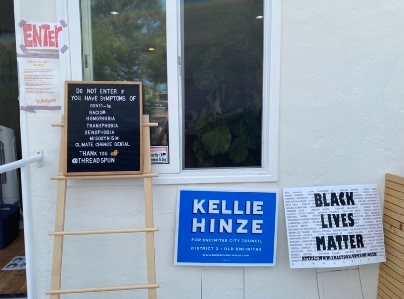 There are political signs outside of local Encinitas businesses. Many small businesses show their support for political candidates and movements by displaying signs and posters by their stores. 