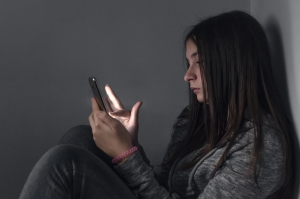 A student scrolls through social media unaware of its influence on her. The effects of social media can be harmful if screen time is not moderated. 