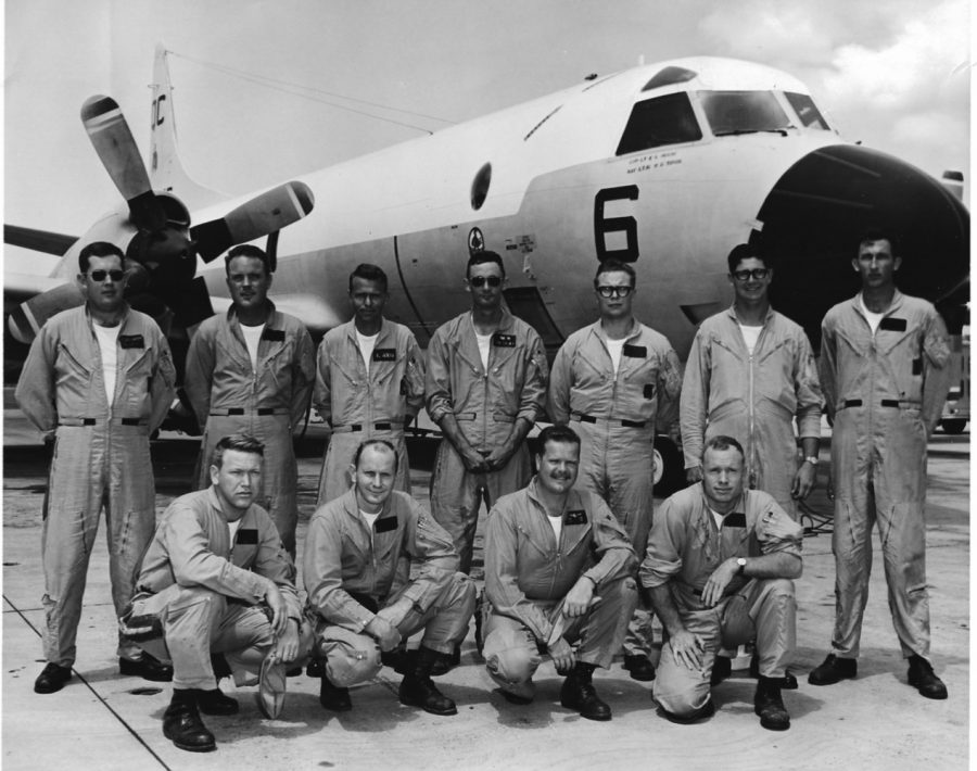 Lewis stands with his team in front of an airplane. Lewis held the title of a naval aviator during his service. 