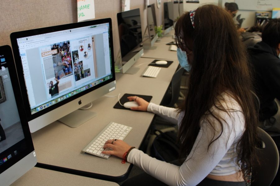 A Student works on composing a page of the Sage Creek yearbook while peers gather interviews and photos for the class around campus. In Publication Journalism, students work towards producing the end-of-the-year purchasable yearbook. They gather images and student quotes before composing every page with a theme in mind. 