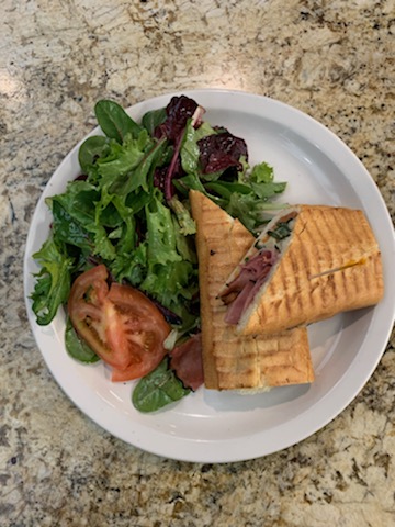 A famous and delicious beef panini is served with a side of tomatoes and a salad with dressing. The Cafe and Bakery does not only serve pastries and dessert items, it also has lunch and dinner meals as well.
