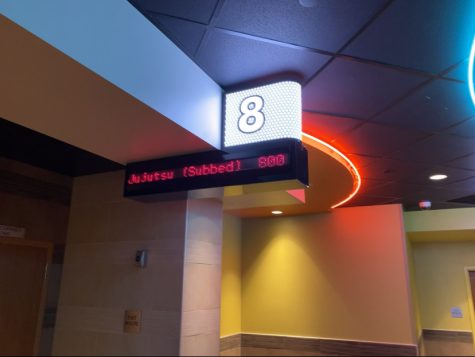 A screen at Regal Theater displays the title and showtime of a Jujutsu Kaisen Showing. In the US, the movie was released in both an English dub, and the original Japanese with English subtitles. 