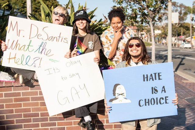 GSA club members Jackson Connolly, Yessenia Sanchez, Ariella Cummins and Benjamin Mendez hold up signs in the village, protesting new bill HB 1557 in Florida. Everyone in the photo here is a part of the LGBT youth club, GSA, at Carlsbad High School. 