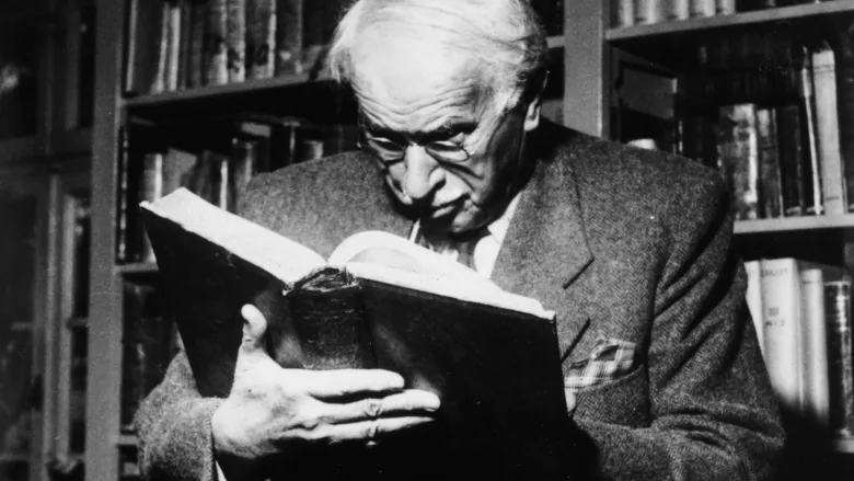 Carl Jung reads a book while sitting in a library. Jung was the first person to publish developed ideas concerning MBTI and personality theories.