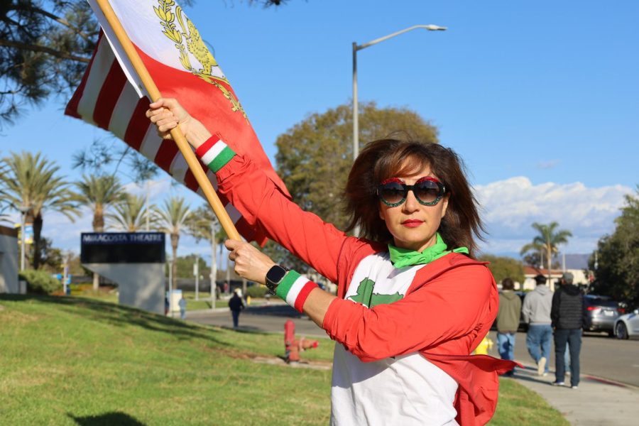 A protester waves an Iranian flag in support of freeing Iran in front MiraCosta College. During his speech on Thursday, Biden assured the audience that Iranians will “free themselves pretty soon”.  