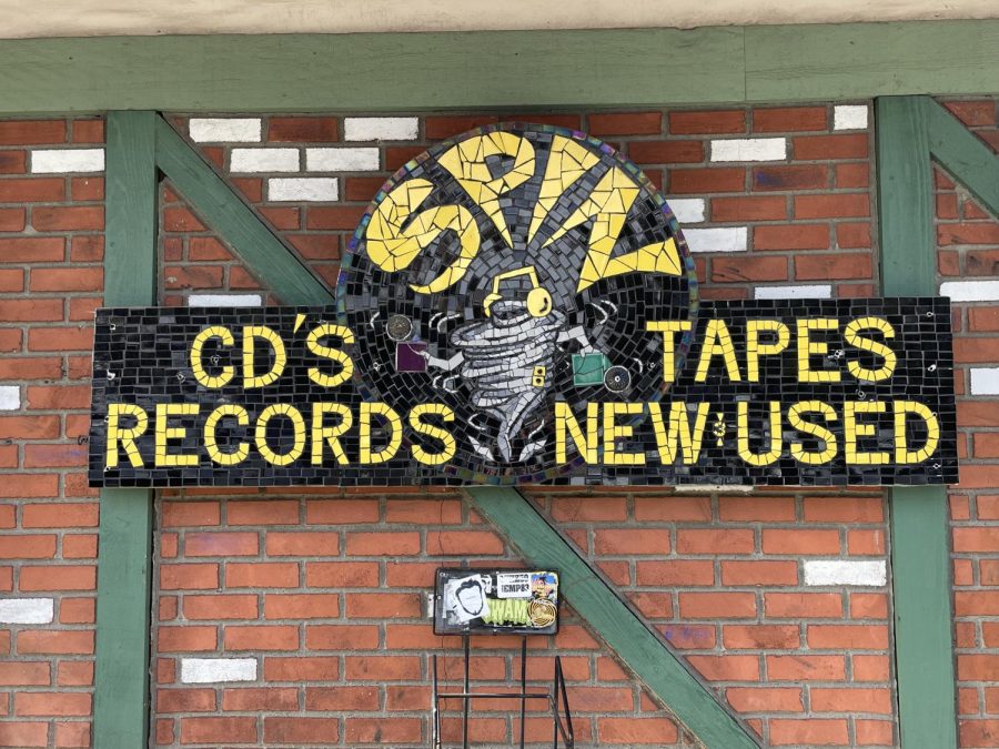 Outside of the Spin Records business, a mosaic of Spin’s signature headphone-wearing cyclone advertises their sales of CD’s, tapes, and records both new and used. Inside the store, many different store merchandise items can be found with this logo printed on them. 