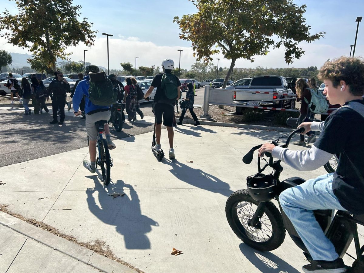 Students bike among cars and pedestrians.