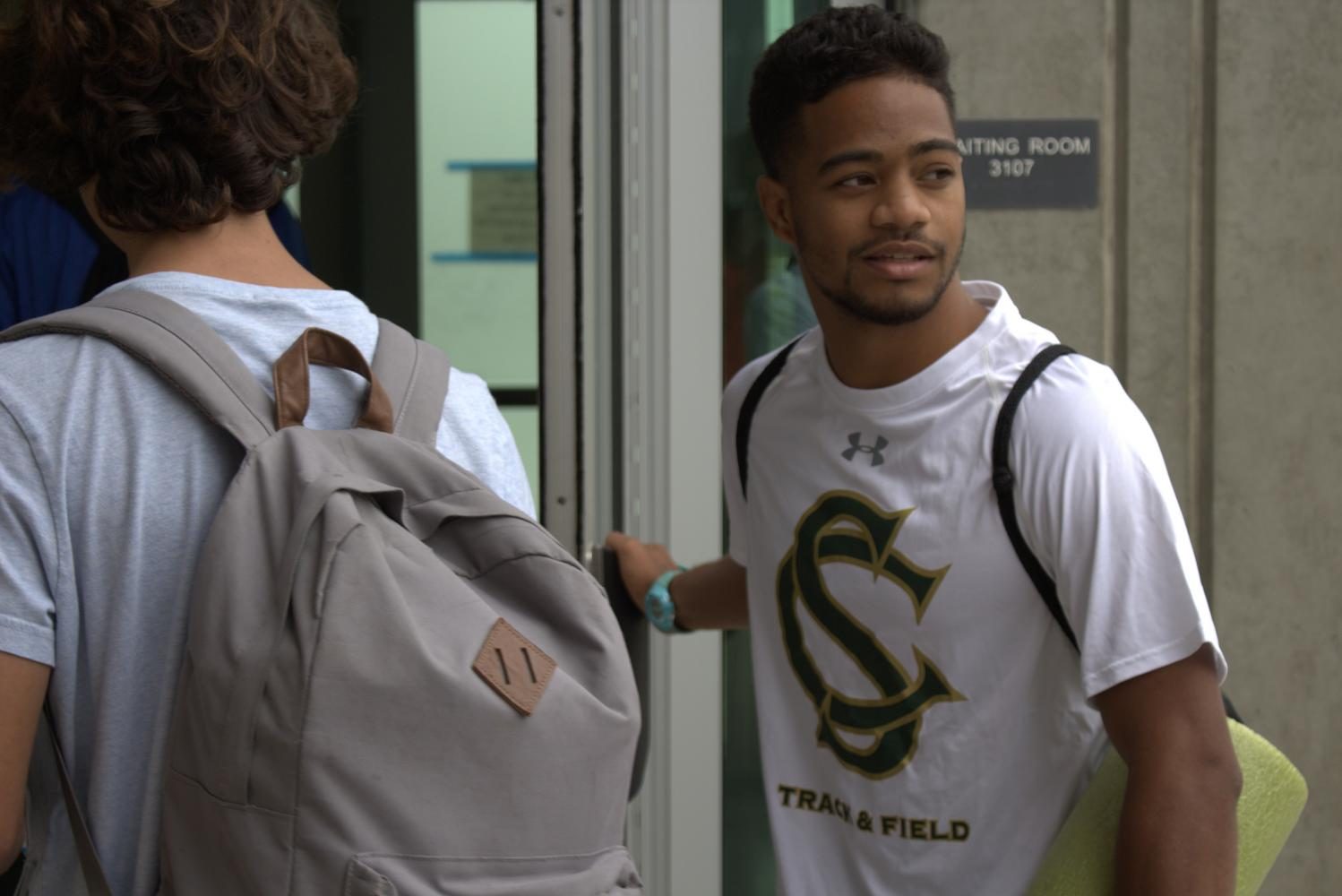 Coach Jamal Brewer holds open the door for his team before going to an away meet.