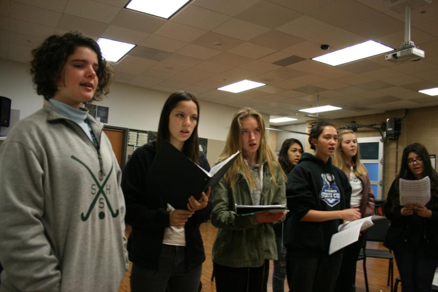 The choir stands while practicing the alma mater. The class is spending time
learning the song for the hoopcoming assembly.