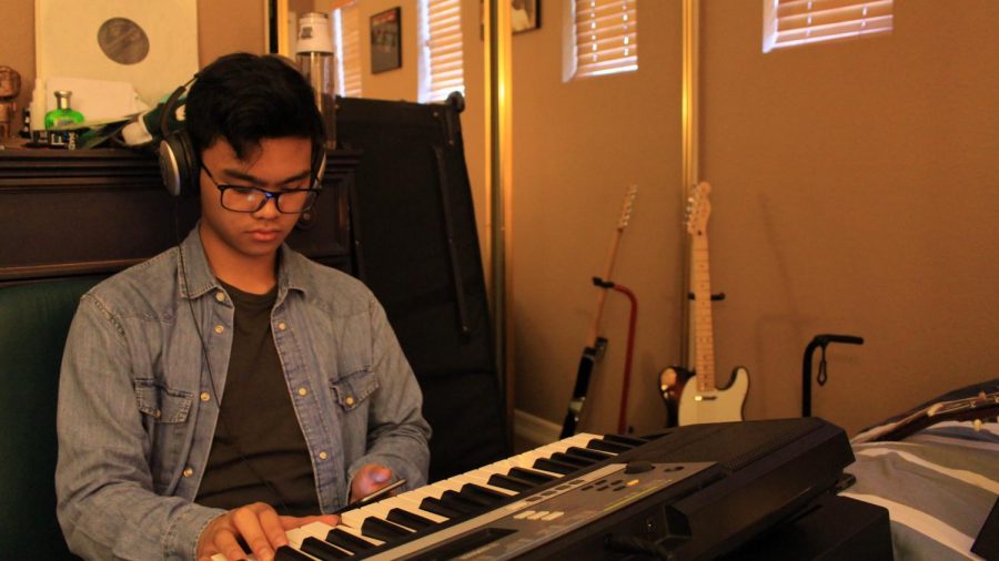 Senior Ivan Florentino listens to a recording of a keyboard accompaniment, learning how to play it measure by measure.