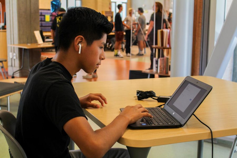 A freshman student signs into his newly issued Chromebook. Convenient charging stations were provided in the library for student access.