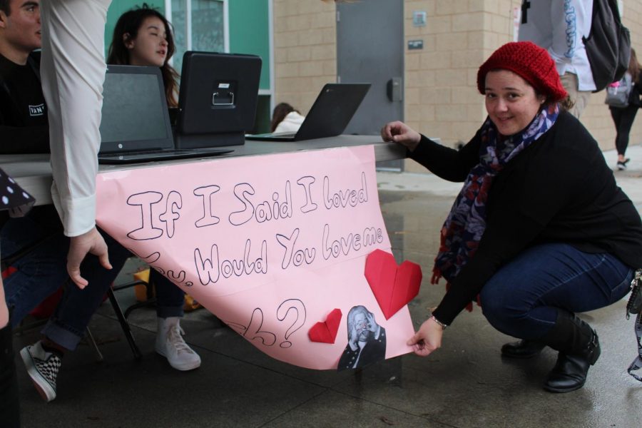 Ms. Quinones, the choir director, holds up the Valentines grams sign on a windy Monday morning. Choir is selling Valentines grams until Feb. 13 to raise money for the choir program and spread a little love around the campus. 