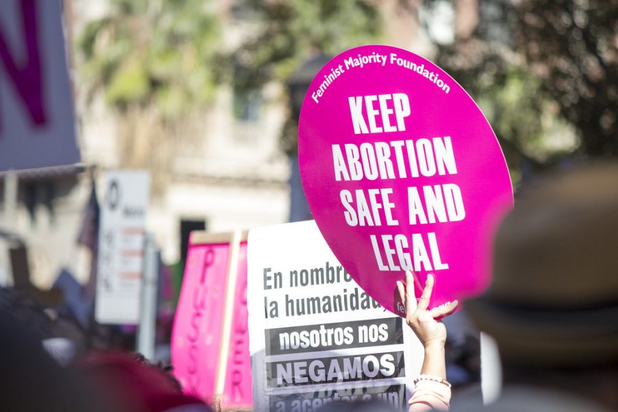 A woman carries a sign in a protest to protect the right to her own body. Women have been marching in protest for various rights they have been denied for over a hundred years now.