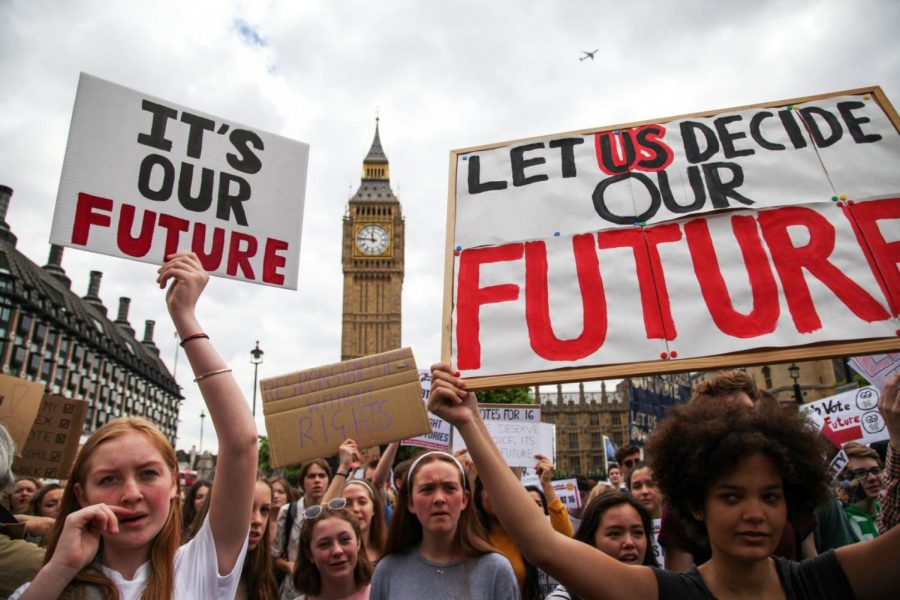 Persons between the age of 14 and 16 hold up signs encouraging the legal voting age to be dropped to the age of 16. Though this protest occurred across waters in London, this state of mind is held among young people globally. 