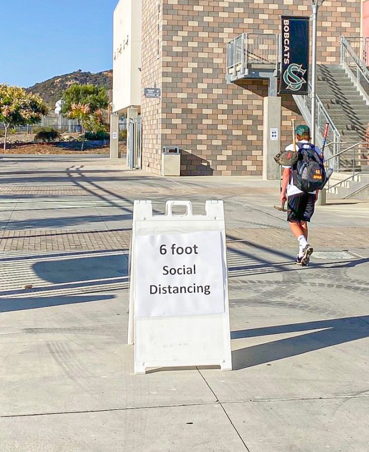 A student heads to practice while passing a sign reinforcing social distancing on Oct. 13. Social distancing is one of the ten protocols to ensure on-campus safety. 