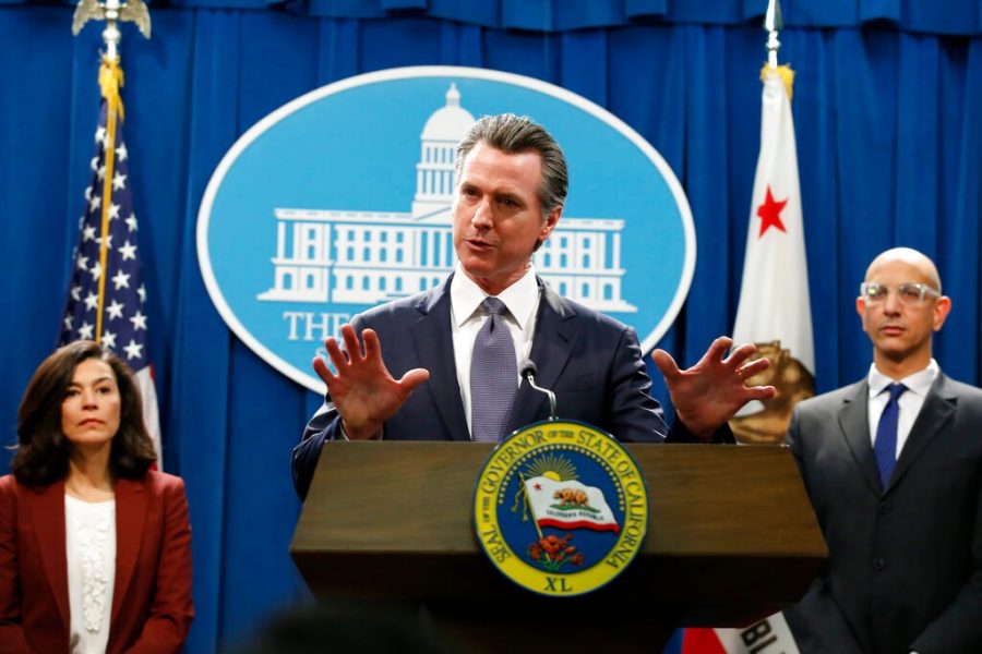 California Gov. Gavin Newsom speaks to reporters about the state's response to the coronavirus during a news conference in Sacramento, Calif. Newsom, a Democrat who leads the nation's most populous state, has won praise from both sides of the aisle for his approach to the coronavirus crisis though he's been less aggressive than some other governors and local leaders. Newsom is accompanied by California Department of Public Heath Director and State Health Officer Dr Sonia Angell, left, and California Health and Human Services Agency Director Dr. Mark Ghaly, right. 