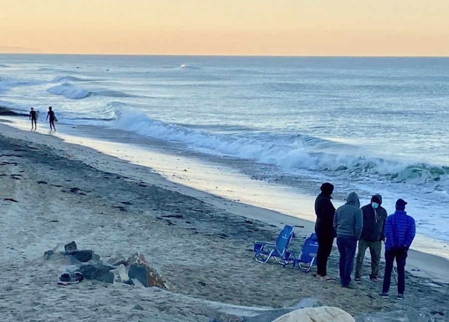 A small group of men are gathered in prayer during sunrise while two Sage Creek freshmen head out to surf. Despite the weather getting colder, surfers still enjoy the winter swells. 