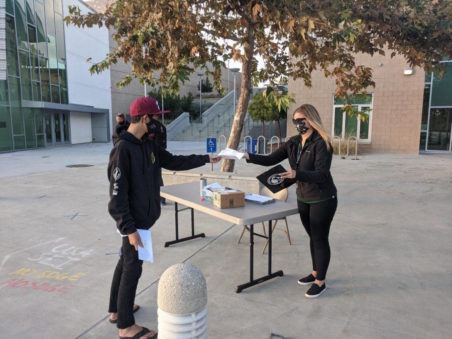 Athletic Director, Andrea Williams helps student Jack Donnelley as he submits his athletic clearance forms for the fall season. Williams had a table set up and stayed masked up as she assisted students so that they can participate in their athletic extracurriculars.