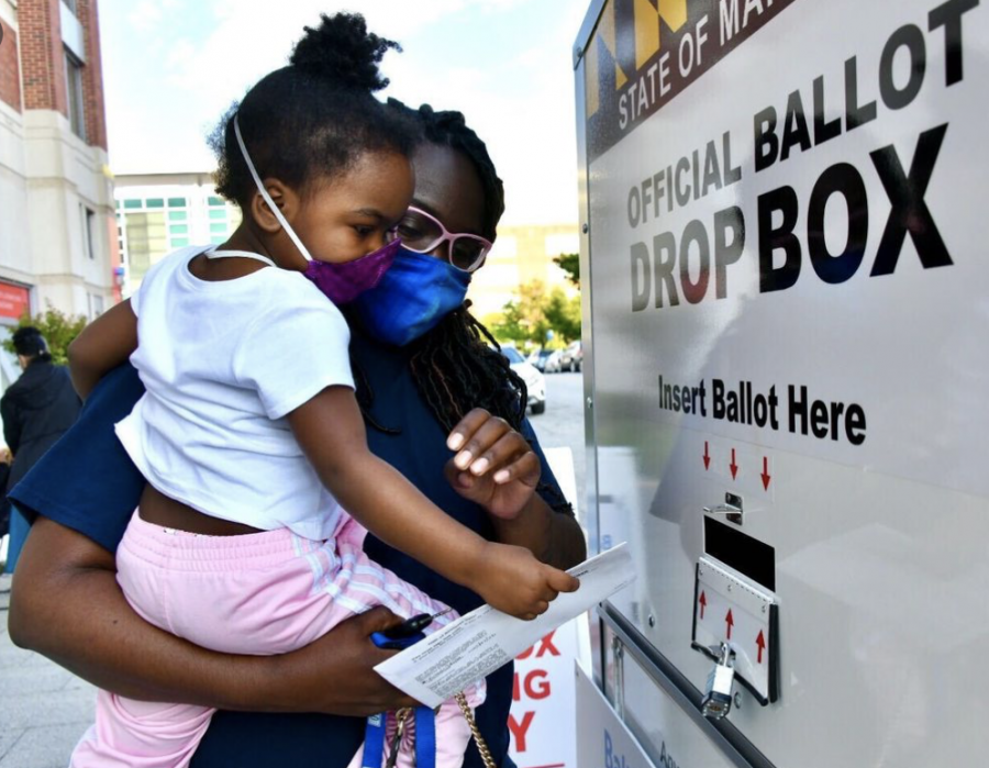 A voter drops in their ballot into the official ballot drop box. Many Americans used these ballot boxes located at polling stations to combat the long Election Day lines.