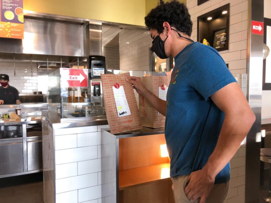 A customer at Noodles & Company picks up their contactless order. Noodles & Company has been following COVID-19 restrictions closely and has made their online orders safer to obtain with contactless pickups and free food delivery through Nov. 15.  