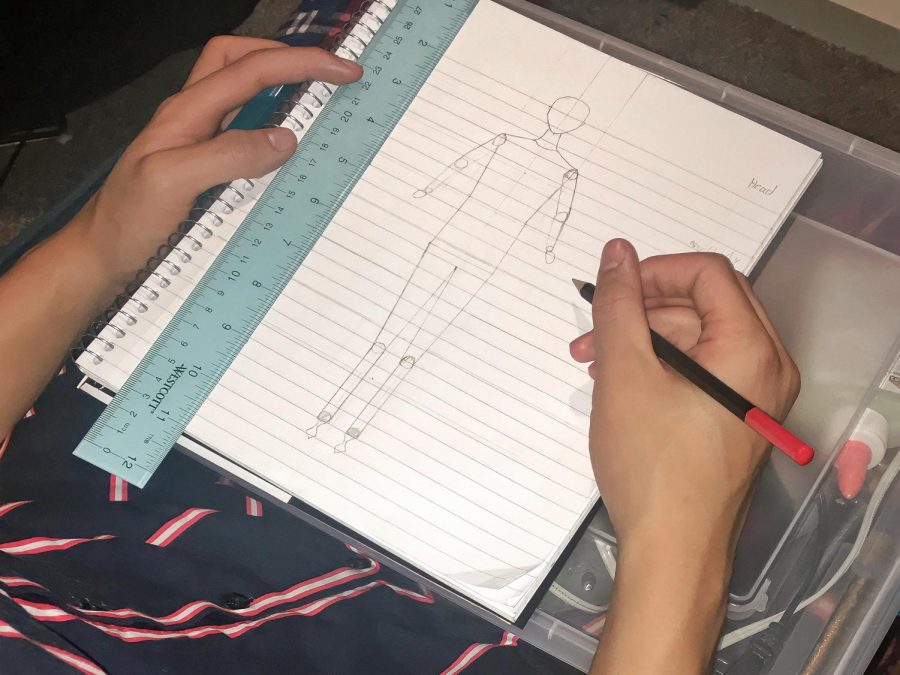 Junior Zachary Ramos sketches a croquis for Fashion Club. A croquis is a sketch that fashion designers draw to get an idea of what type of piece they want to create, something the club is working on as prep before designing.