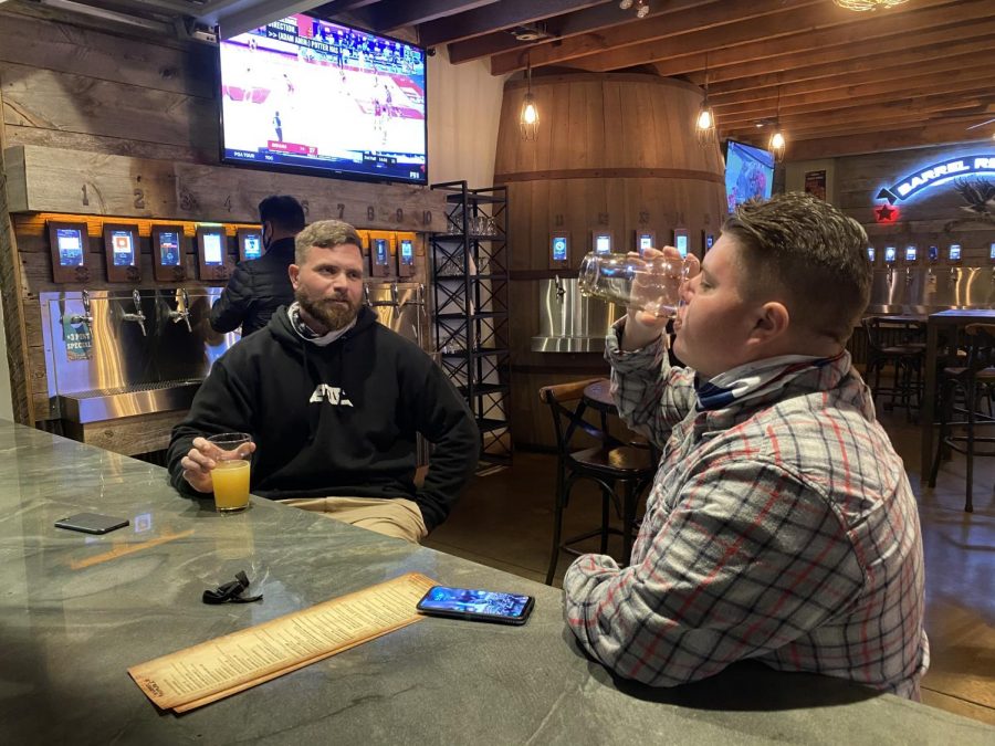 Two men are drinking in a local bar. Restaurants and other attractions have reopened, causing swarms of people to go back to their old normal. 