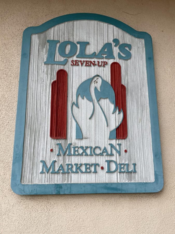 Lola’s 7 Up Mexican Market and Deli sign is plastered to the side of the restaurant building. Lola’s is a family-owned business that officially started selling their authentic Mexican food on March 17, 1986.  