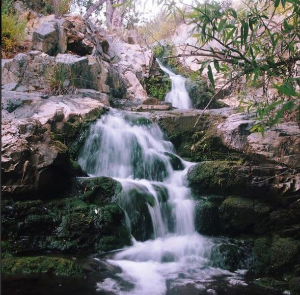 Water cascades from Copper Creek Falls on a bright, sunny day. Come take an adventurous hike to the mine from the early 1900s and the serene falls!