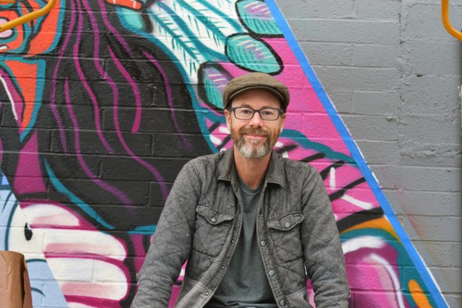  Snyder poses in front of the art wall. The community artist aims to open the wall at an approximate time of the start of the new year. 