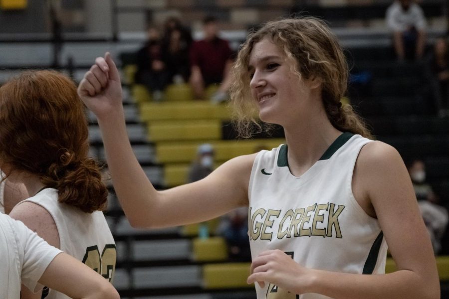 Sophomore Hannah Keehn raises her hand in solidarity with her teammates during a huddle. The team took the lead throughout the game. 