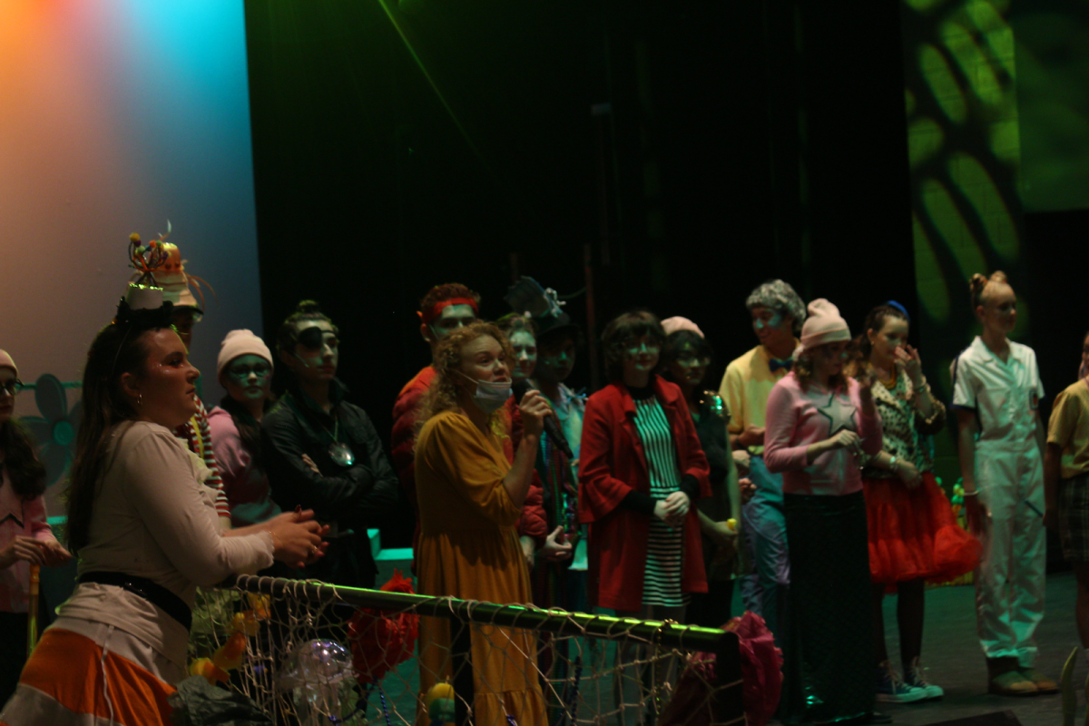 Mrs. Porter leads a Q&A at the end of SpongeBob Musical. She stands with her students in the crowd. 
