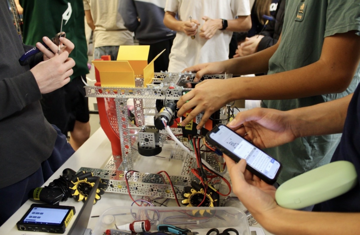  Team members are working on figuring out what they need for the robot. One of them has their phone out, ready to place the order.